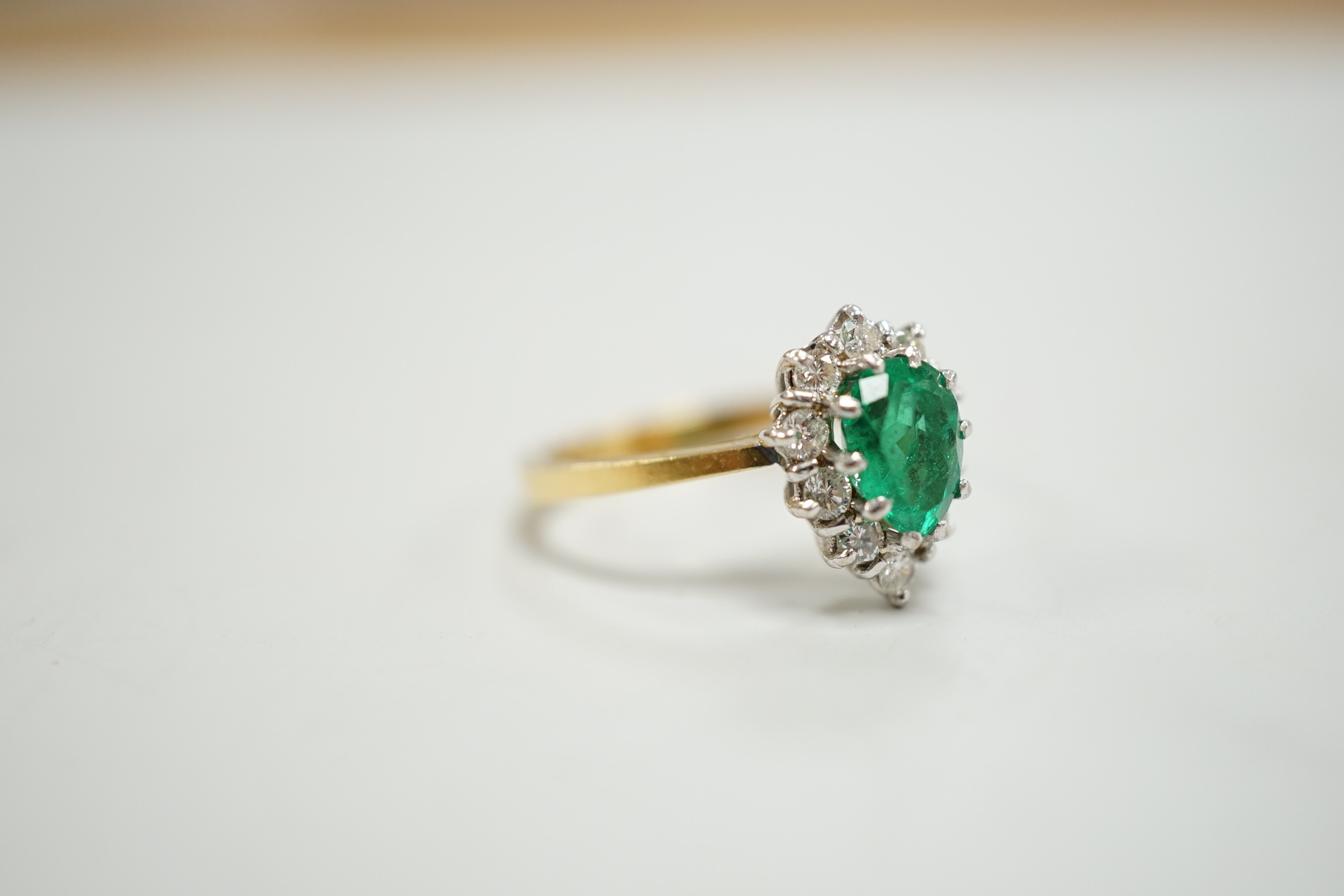 A modern 18ct gold, single stone emerald and diamond chip set pear shaped cluster ring, size M/N, gross weight 3.9 grams.